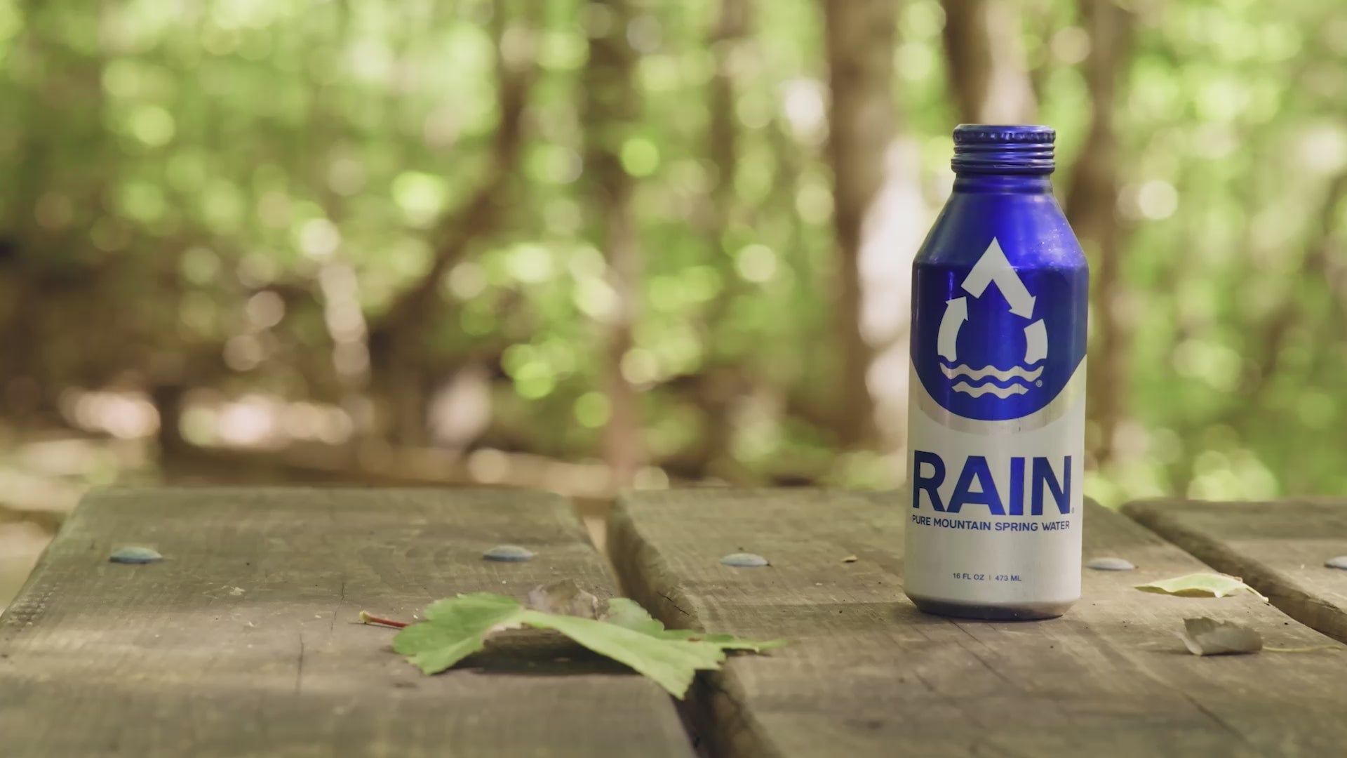 RAIN bottle on a table while a woman walks away in the background.