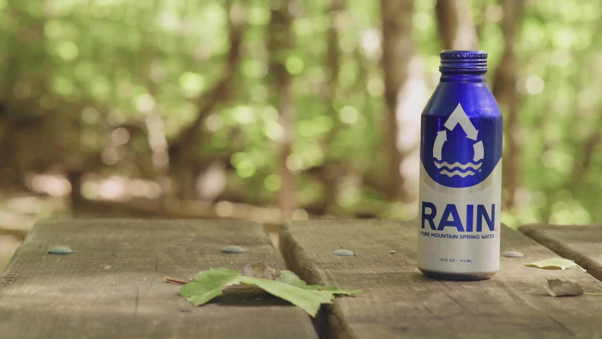 RAIN bottle on a table while a woman walks away in the background.